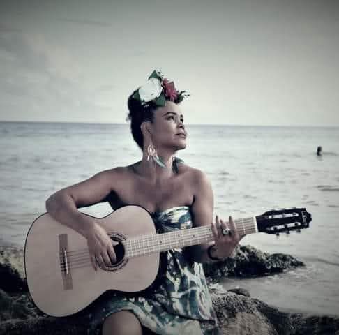 Neuz Ferreira tocando guitarra junto al mar